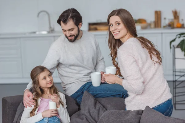 Happy parents and daughter with drinks in morning — Stock Photo