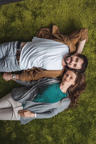 Top view of attractive couple lying on green carpet at home — Stock Photo