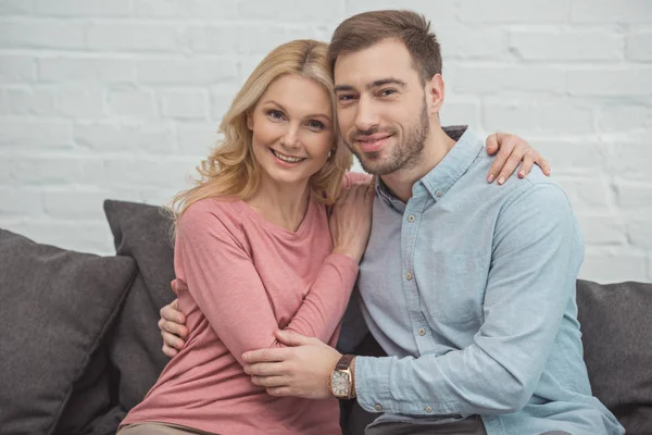 Portrait of smiling mother and grown son hugging each other while sitting on sofa — Stock Photo