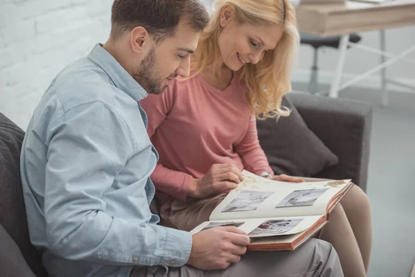 Happy family looking at photos in photo album together at home — Stock Photo