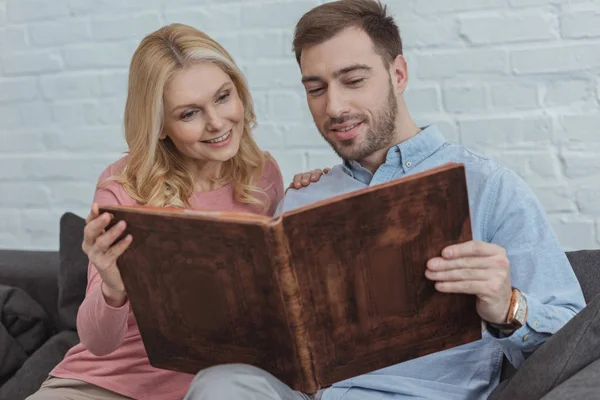 Familia feliz mirando fotos en álbum de fotos juntos en casa - foto de stock