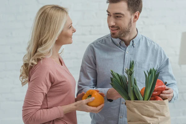 Retrato de hijo y madre crecidos con bolsa de papel llena de verduras frescas para la cena en casa - foto de stock