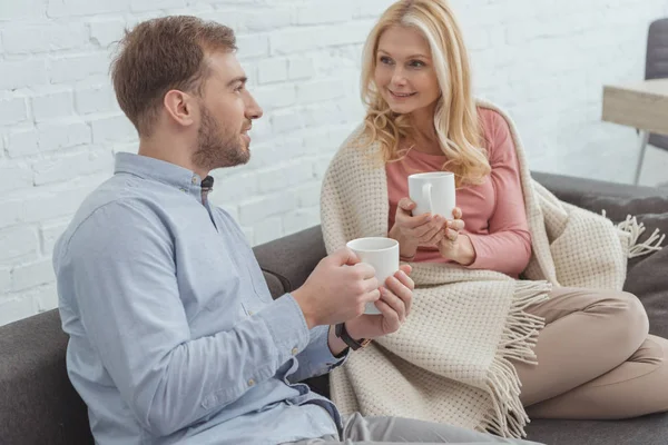 Família sorrindo com xícaras de café descansando no sofá — Fotografia de Stock