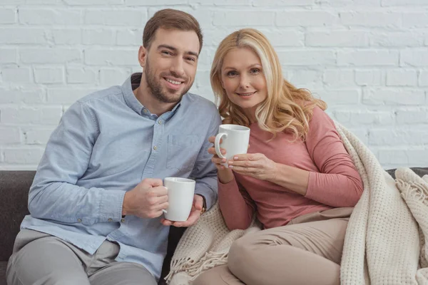 Ritratto di una famiglia sorridente con tazze di caffè appoggiate sul divano — Foto stock