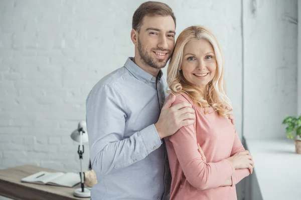 Porträt eines erwachsenen Sohnes, der die glückliche Mutter zu Hause umarmt — Stockfoto