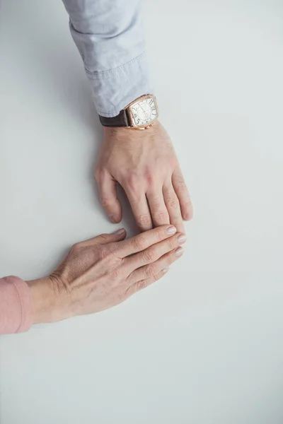 Teilansicht von Mutter und erwachsenem Sohn beim Händchenhalten auf weißer Tischplatte — Stockfoto