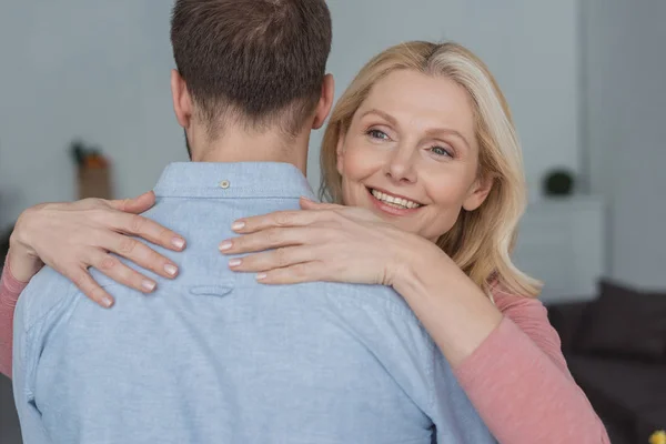 Ritratto della madre sorridente che abbraccia il figlio cresciuto — Foto stock