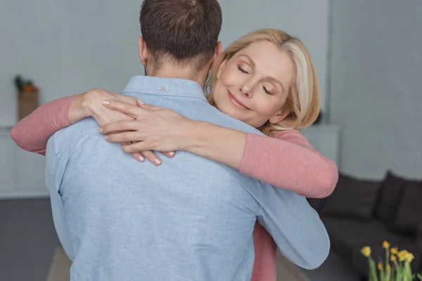 Porträt einer lächelnden Mutter, die ihren erwachsenen Sohn umarmt — Stockfoto