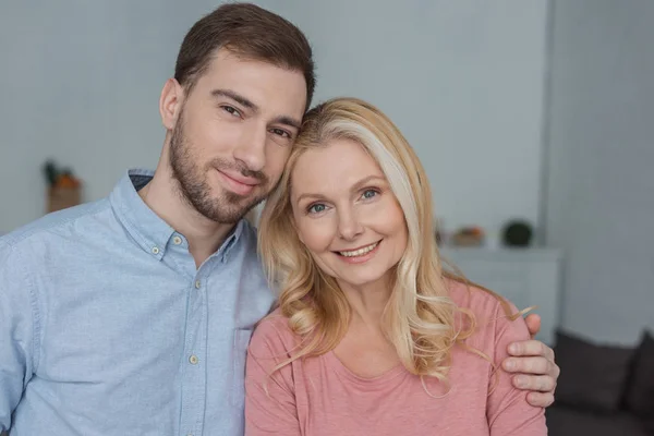 Portrait of grown son hugging smiling mother and looking at camera — Stock Photo
