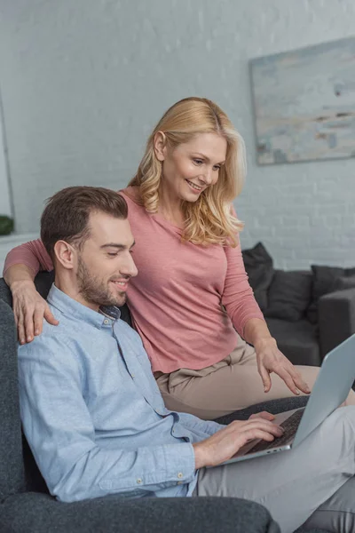 Visão lateral da mãe e do filho crescido usando laptop juntos em casa — Fotografia de Stock