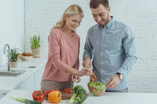 Retrato de família cozinhando salada para jantar juntos em casa — Fotografia de Stock