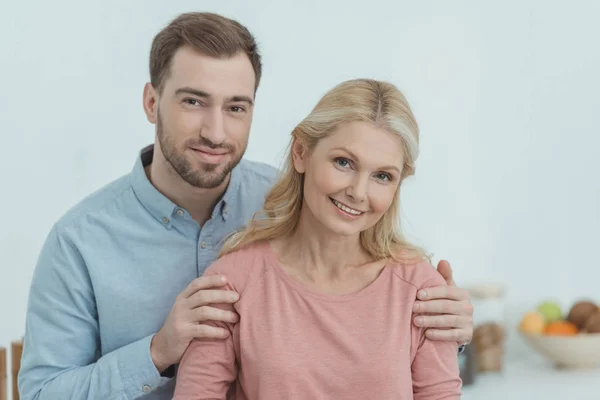 Ritratto del figlio adulto che abbraccia la madre sorridente — Foto stock