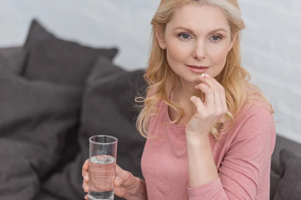 Ritratto di donna matura con bicchiere d'acqua e medicina in mano — Foto stock