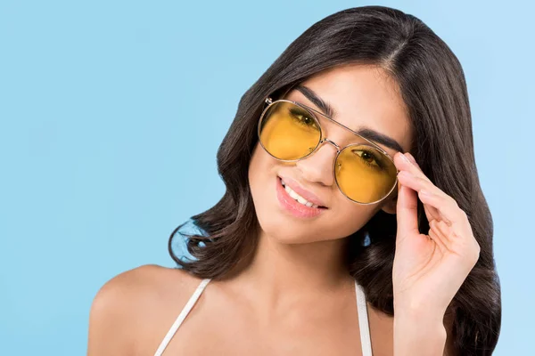 Beautiful smiling girl posing yellow sunglasses, isolated on blue — Stock Photo