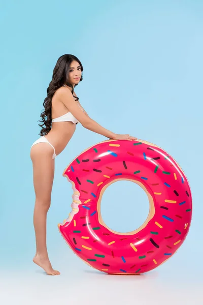 Attraktives Mädchen posiert mit aufblasbarem Donut-Ring, isoliert auf blau — Stockfoto