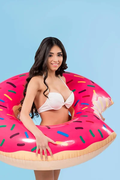 Menina atraente em maiô posando com anel de donut inflável, isolado em azul — Fotografia de Stock