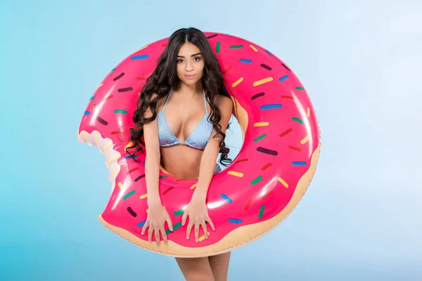 Menina elegante atraente posando com anel de donut inflável, isolado em azul — Fotografia de Stock