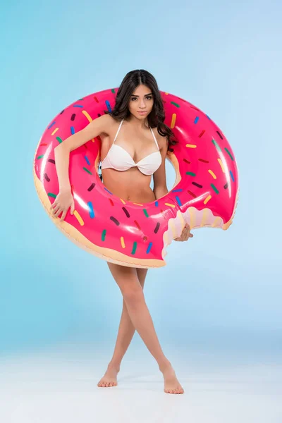Schönes Mädchen posiert mit aufblasbarem Donut-Ring, isoliert auf blau — Stockfoto