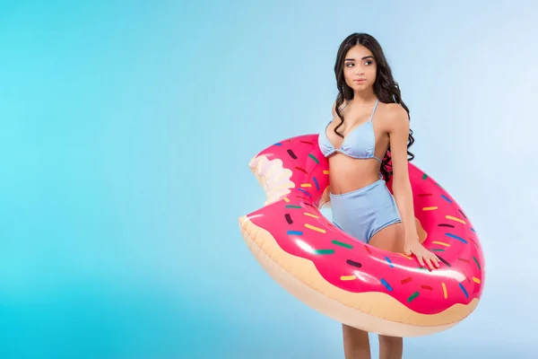 Красива дівчина позує з надувним кільцем пончика, ізольована на синьому — стокове фото