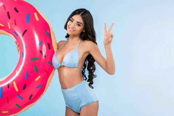 Chica atractiva con anillo de rosquilla inflable, aislado en azul - foto de stock