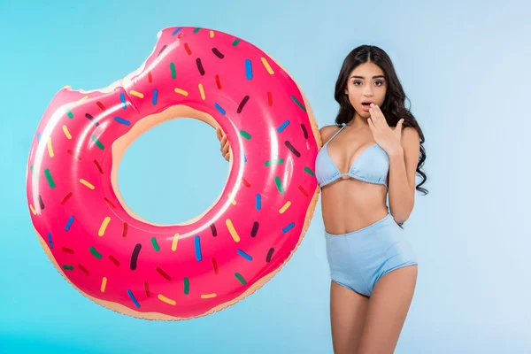 Menina chocada atraente com anel inflável do donut, isolado no azul — Fotografia de Stock