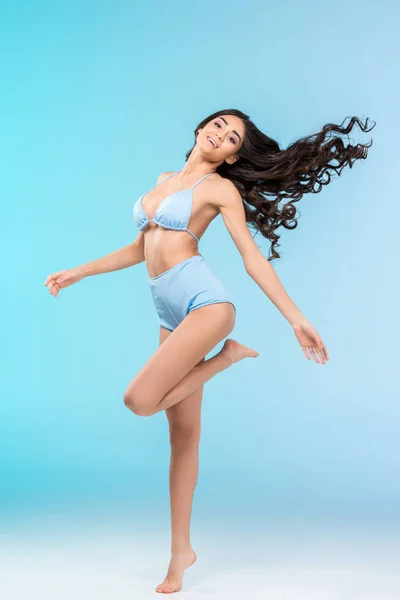 Hermosa chica morena feliz posando en bikini, aislado en azul - foto de stock