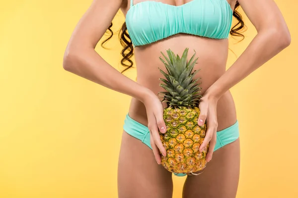 Vista ritagliata della ragazza abbronzata che tiene frutta ananas, isolato su giallo — Foto stock