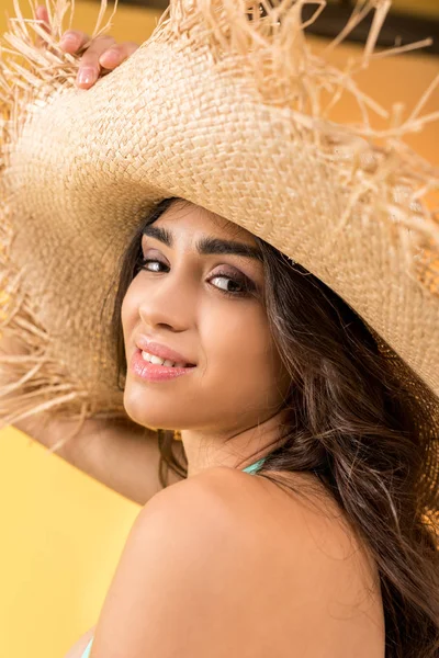 Portrait of beautiful smiling girl posing in straw hat, isolated on yellow — Stock Photo