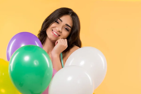 Glückliches Mädchen posiert im Bikini mit bunten Luftballons, isoliert auf gelb — Stockfoto