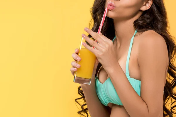 Vista ritagliata di ragazza in posa con vetro di succo di frutta, isolato su giallo — Foto stock