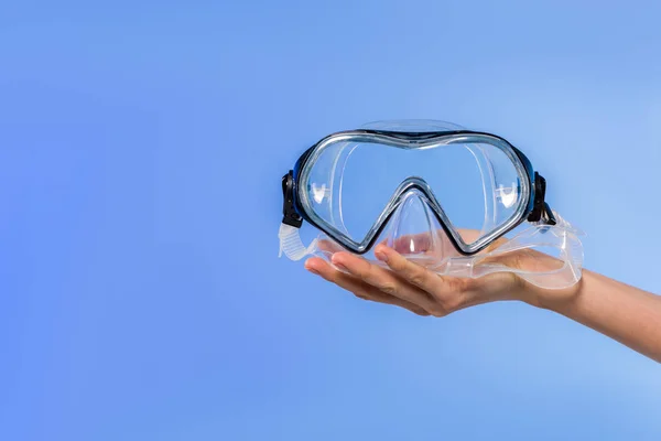 Vista recortada de la mano femenina con gafas de natación, aisladas en azul - foto de stock