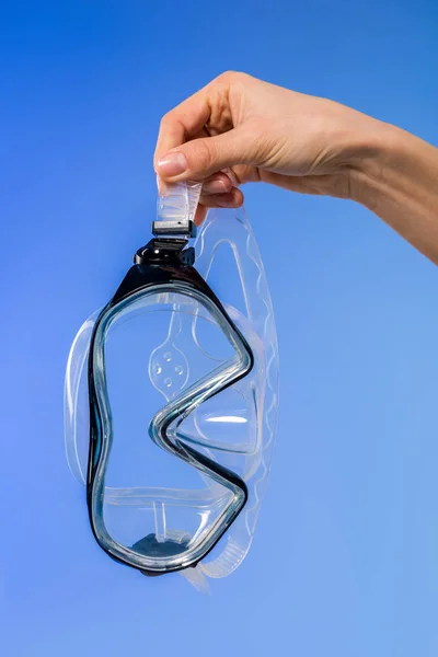 Cropped view of female hand with swimming mask, isolated on blue — Stock Photo