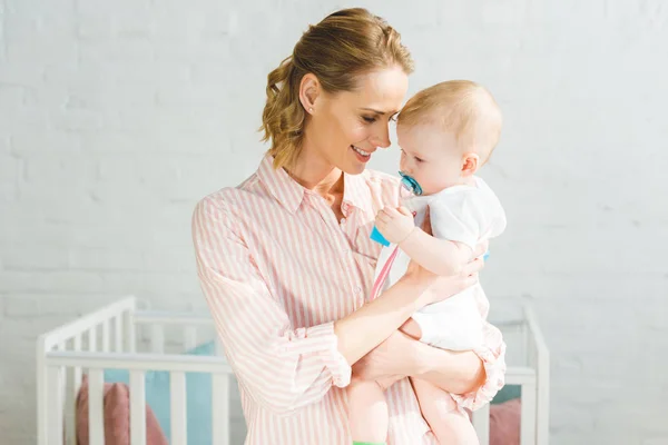 Junge Mutter hält kleine Tochter mit Babyattrappe — Stockfoto