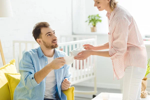 Jeune femme versant le thé à petit ami avec tasse à la main — Photo de stock