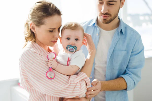 Parents standing with infant daughter with baby dummy — Stock Photo
