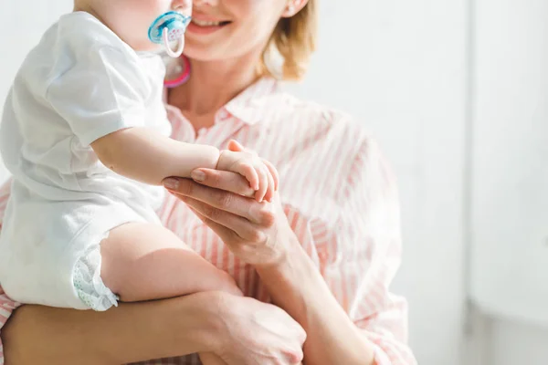 Abgeschnittenes Bild einer Mutter, die ihre kleine Tochter mit Babyattrappe hält — Stockfoto
