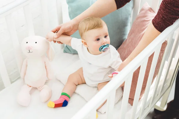 Imagem cortada da mãe segurando a filha infantil sentada no berço — Fotografia de Stock