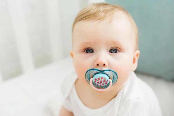 Portrait of infant with baby dummy in crib — Stock Photo