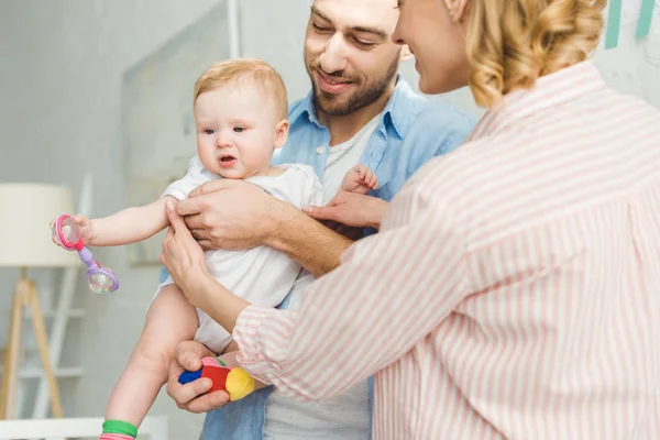 Молодые родители держат в руках новорожденную дочь с игрушкой — стоковое фото