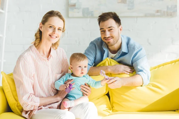 Mutter hält Säuglingstochter, während Vater ihr Spielzeug gibt — Stockfoto