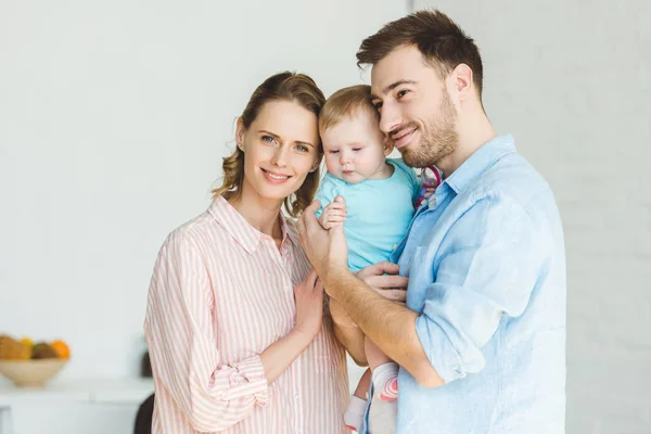 Молода усміхнена сім'я з немовлям донькою в руках — стокове фото