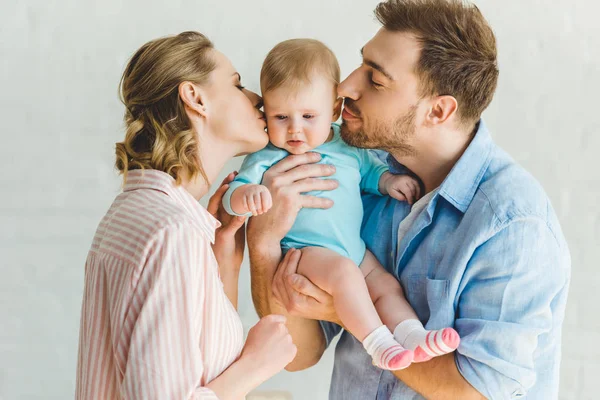 Pais beijando a filhinha e segurando-a nas mãos — Fotografia de Stock