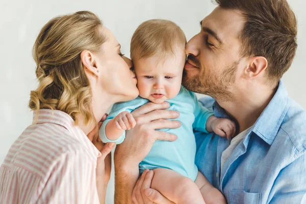 Young parents kissing baby daughter and holding her in hands — Stock Photo