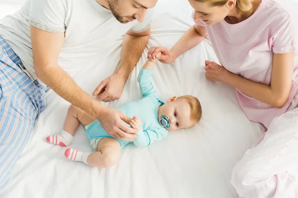 Aus der Vogelperspektive: Eltern berühren kleine Tochter im Bett — Stockfoto