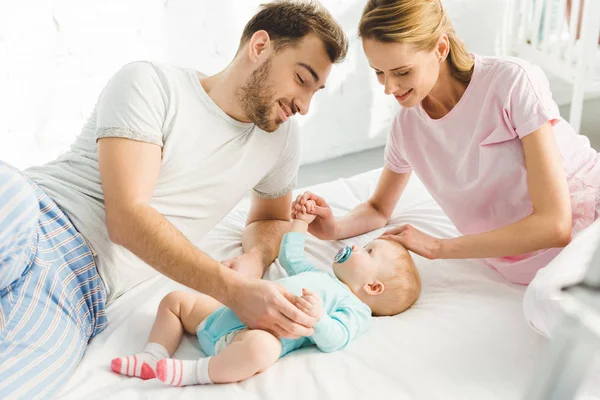 Les jeunes parents touchant la petite fille au lit — Photo de stock