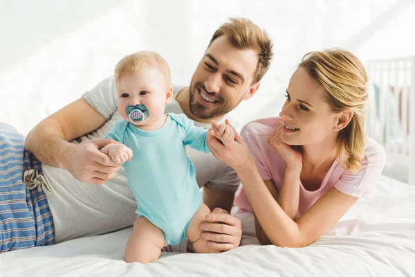 Parents souriants tenant une fille enfant avec mannequin bébé — Photo de stock