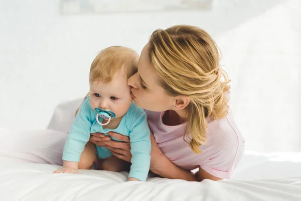 Mutter küsst Säuglingstochter mit Babyattrappe — Stockfoto