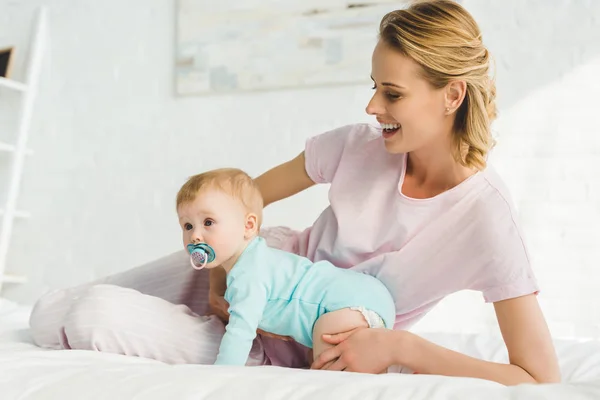 Sonriente madre sosteniendo hija bebé con maniquí bebé — Stock Photo