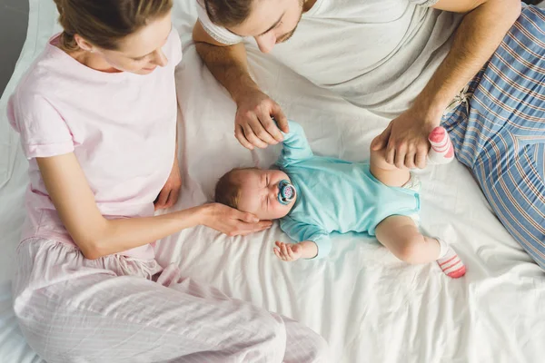 High angle view of parents and crying infant daughter with baby duumy — Stock Photo