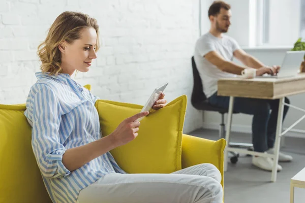 Smiling woman with digital tablet and man typing on laptop — Stock Photo